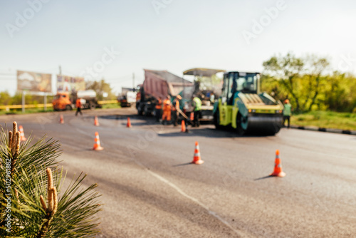 Blur background of construction site is laying new asphalt road pavement,road construction workers and road construction machinery scene.highway construction site landscape