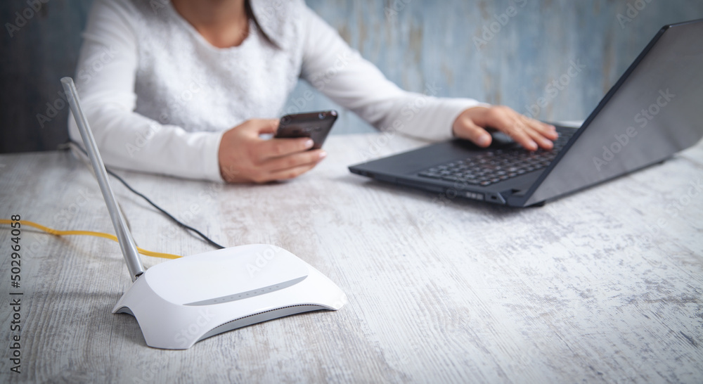 Internet router in the desk. Girl using smartphone Internet router in the desk. Girl using smartphone