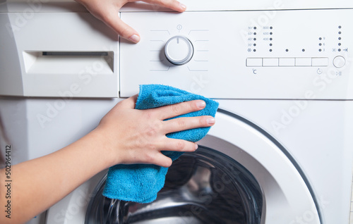 Girl wiping cloth washing machine.