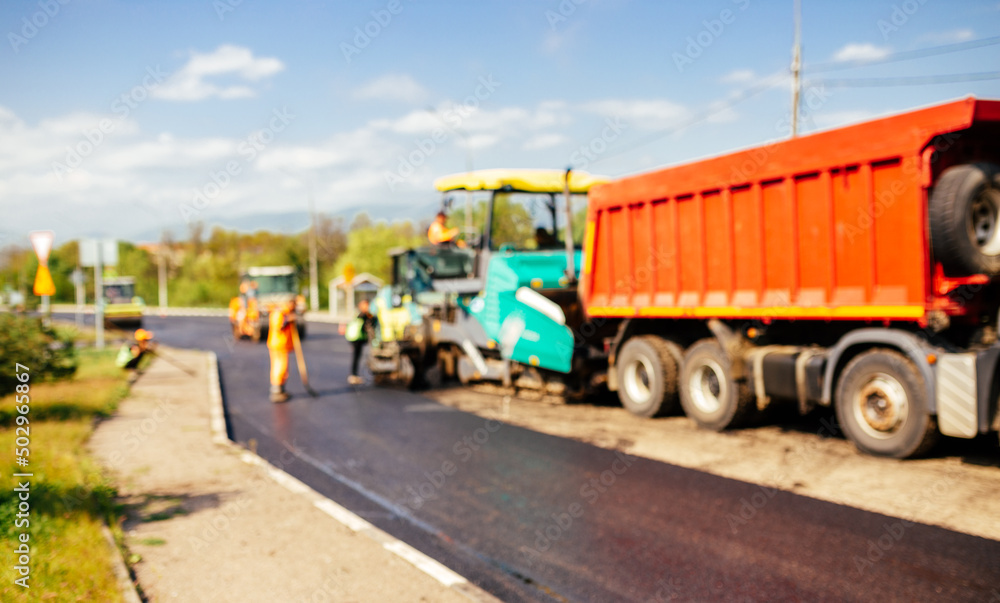 Blur background of construction site is laying new asphalt road pavement,road construction workers and road construction machinery scene.highway construction site landscape