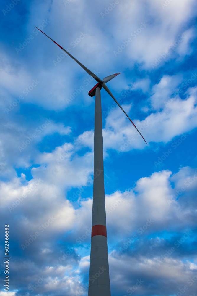 Single wind turbine with cloudy sky in Germany, low angle view. Renewable alternative energy source.