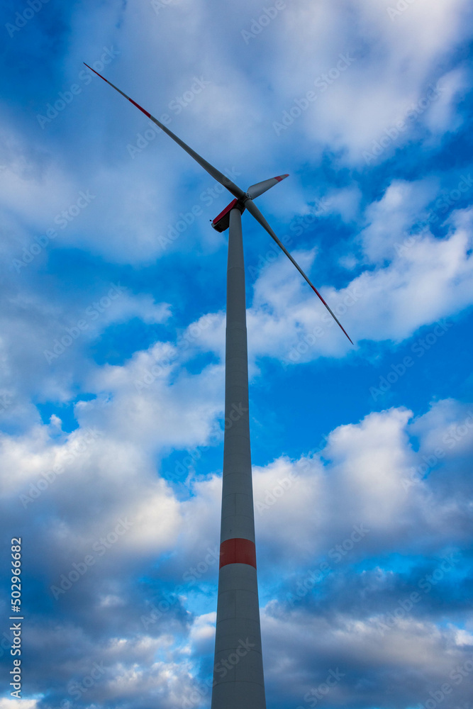 Single wind turbine with cloudy sky in Germany, low angle view. Renewable alternative energy source. Single wind turbine with cloudy sky in Germany, low angle view. Renewable alternative energy source.