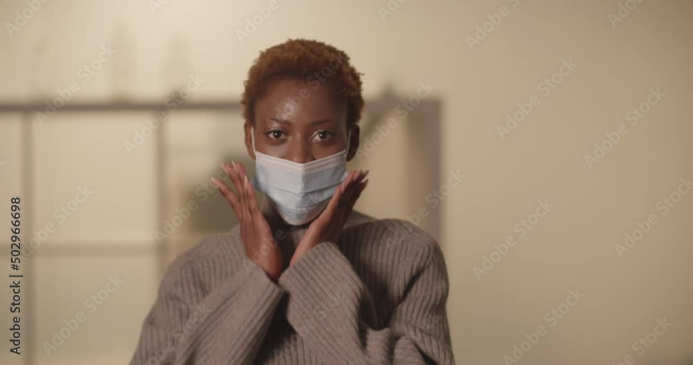 Beautiful smiling young black woman is puts on her covid mask Beautiful smiling young black woman is puts on her covid mask