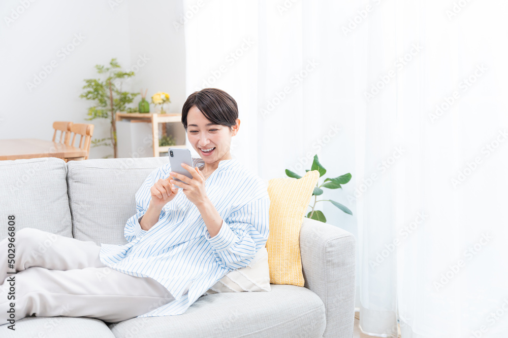ソファーに座るミドル女性(スマホ・メール・インターネット) ソファーに座るミドル女性(スマホ・メール・インターネット)