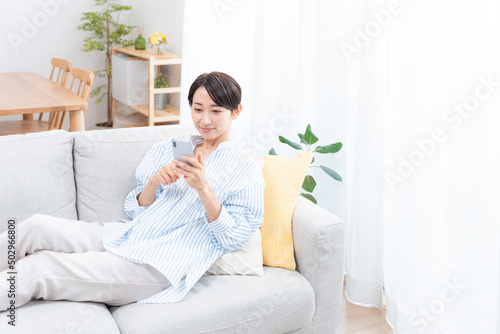 ソファーに座るミドル女性（スマホ・メール・インターネット）