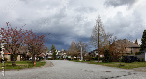 Residential neighborhood Street in Modern City Suburbs. Cloudy Day. Fraser Heights, Surrey, Greater Vancouver, British Columbia, Canada.