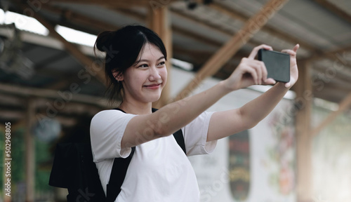 Tourist woman aling selfie with a smartphone while at the train station. Enjoying travel concept. Girl using smartphone while at the railway station platform. photo