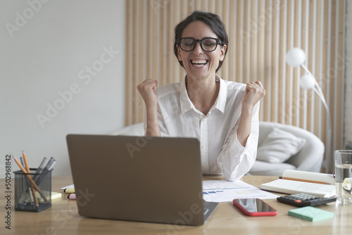 Excited female employee in glasses celebrating success achievement or good work results