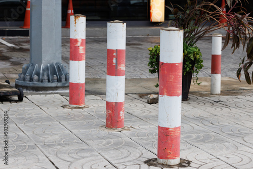 old red and white striped steel bollards on footpath in Thailand.