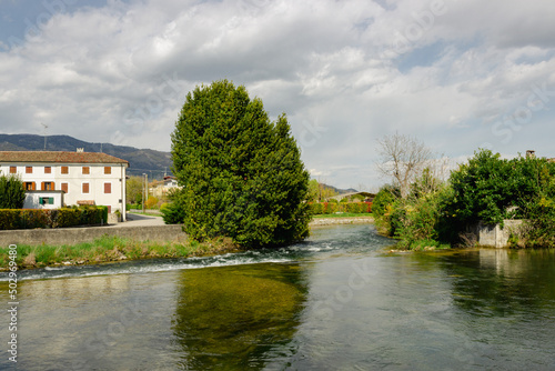 Meschio river flowing among the houses under the cloudy sky.