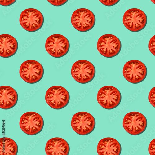 Seamless pattern of slices of ripe tomatoes on a turquoise background