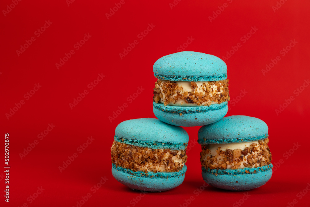French pasta on a red background. Macarons with dor blue and pear. French dessert. Sweet table. Copy space. Place for text.