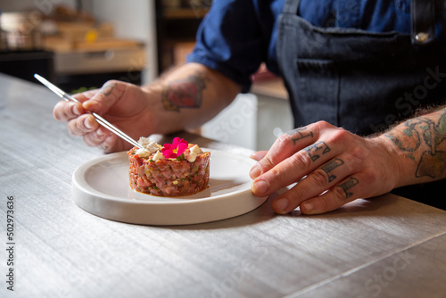 Anonymous chef decorating beef tartare in restaurant photo