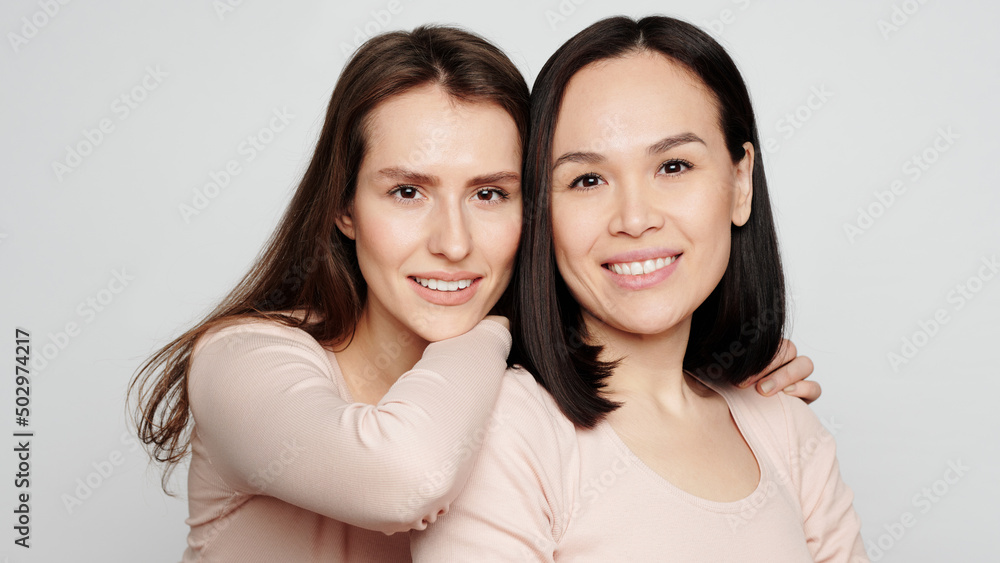 Portrait of positive attractive multi-ethnic girls embracing against white background Portrait of positive attractive multi-ethnic girls embracing against white background