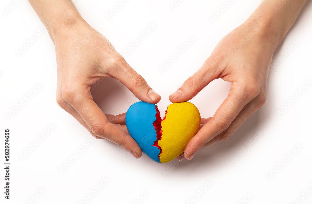 Hands holding a broken heart of Ukraine, war on a white background Hands holding a broken heart of Ukraine, war on a white background