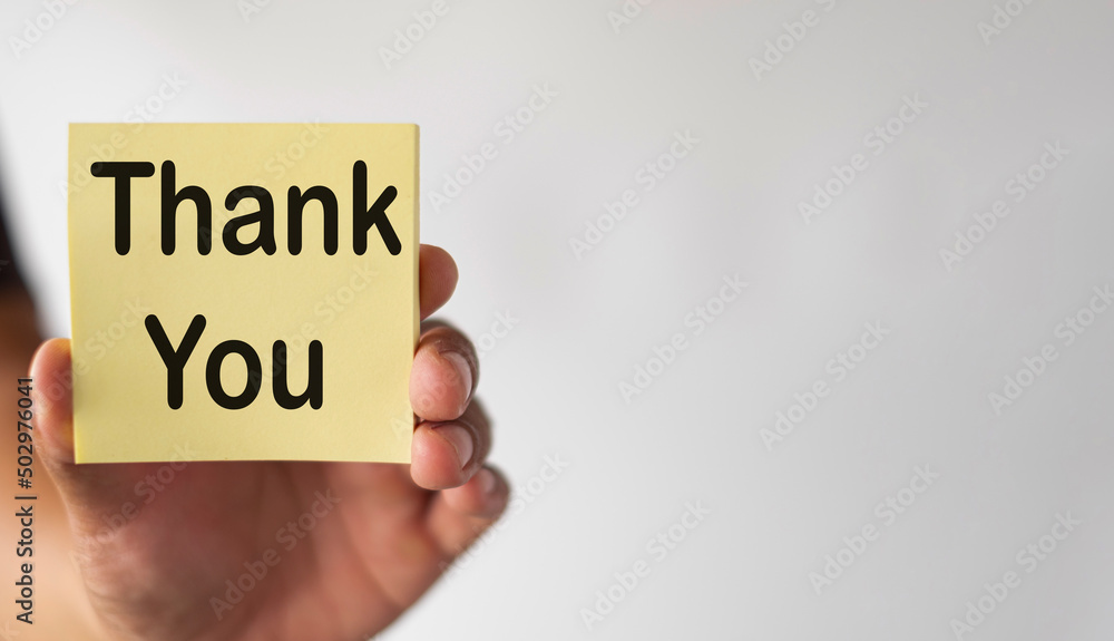 Selective Focus Hand holding yellow sticky note with Thank You word over white background with copyspace. Selective Focus Hand holding yellow sticky note with Thank You word over white background with copyspace.