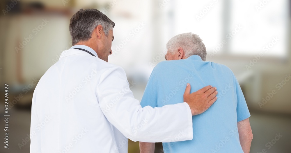 Obraz premium Rear view of caucasian mature male doctor assisting senior man in walking at hospital, copy space