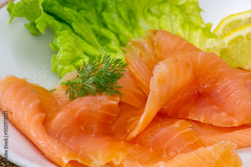 sliced salmon with green lettuce leaves