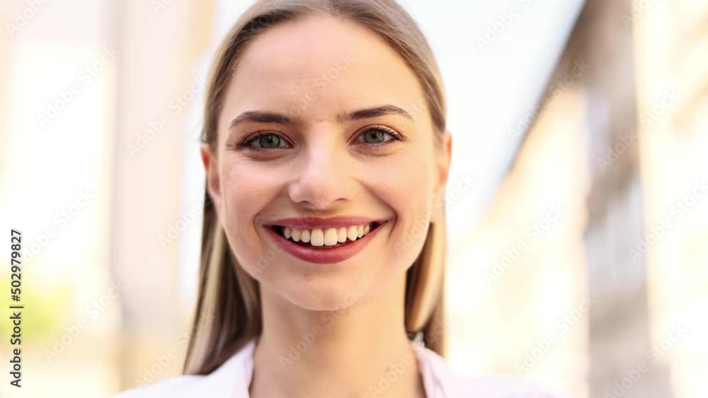 Portrait of attractive blond woman smiling while standing in the city street. Beautiful woman looking ahead outside. Portrait of attractive blond woman smiling while standing in the city street. Beautiful woman looking ahead outside.