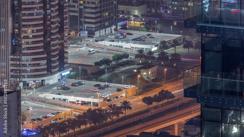 Fototapeta premium Car parking for light vehicles night timelapse in Dubai luxury residential district, aerial view from above.