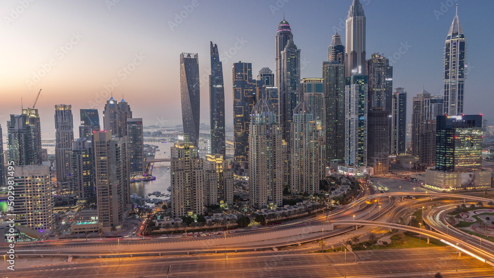 Fototapeta premium Skyscrapers of Dubai Marina near intersection on Sheikh Zayed Road with highest residential buildings day to night timelapse