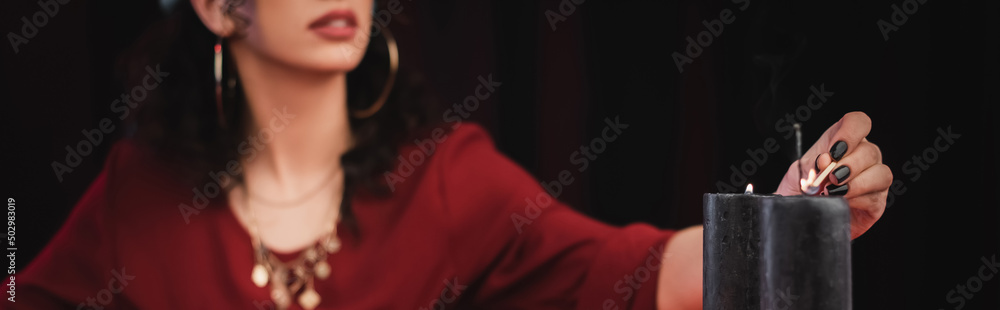 Obraz premium Cropped view of blurred soothsayer burning candle isolated on black, banner.