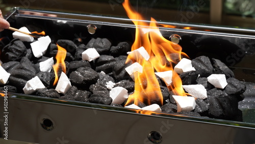 Empty Barbecue Flaming Grill Close Up With Bright Flames And White firelighters burning photo