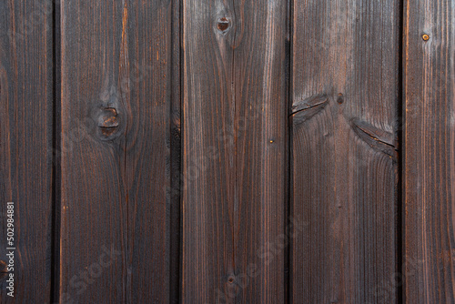 Old brown rural wooden wall on a balcony in dark colors, detailed image texture. Natural wooden building structure, background. Suitable as a flatlay.
