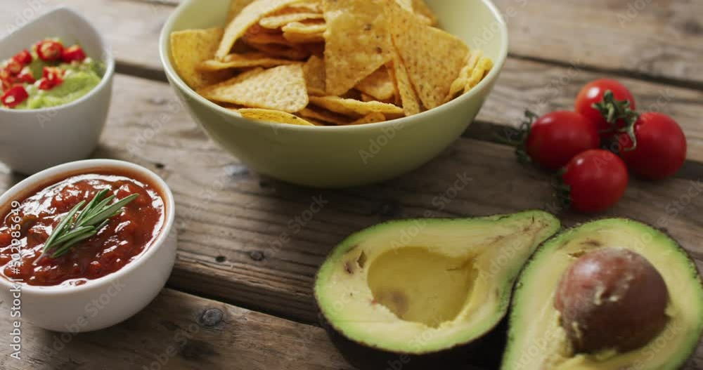 Close up of potato chips in a bowl, sauces and avocado on wooden surface Close up of potato chips in a bowl, sauces and avocado on wooden surface