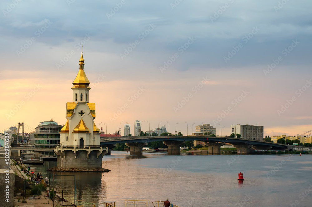Kyiv, Ukraine. July 19. 2014. View of the Dnieper with an Orthodox church in the water, a bridge under construction across the river. Cloudy weather with dramatic skies