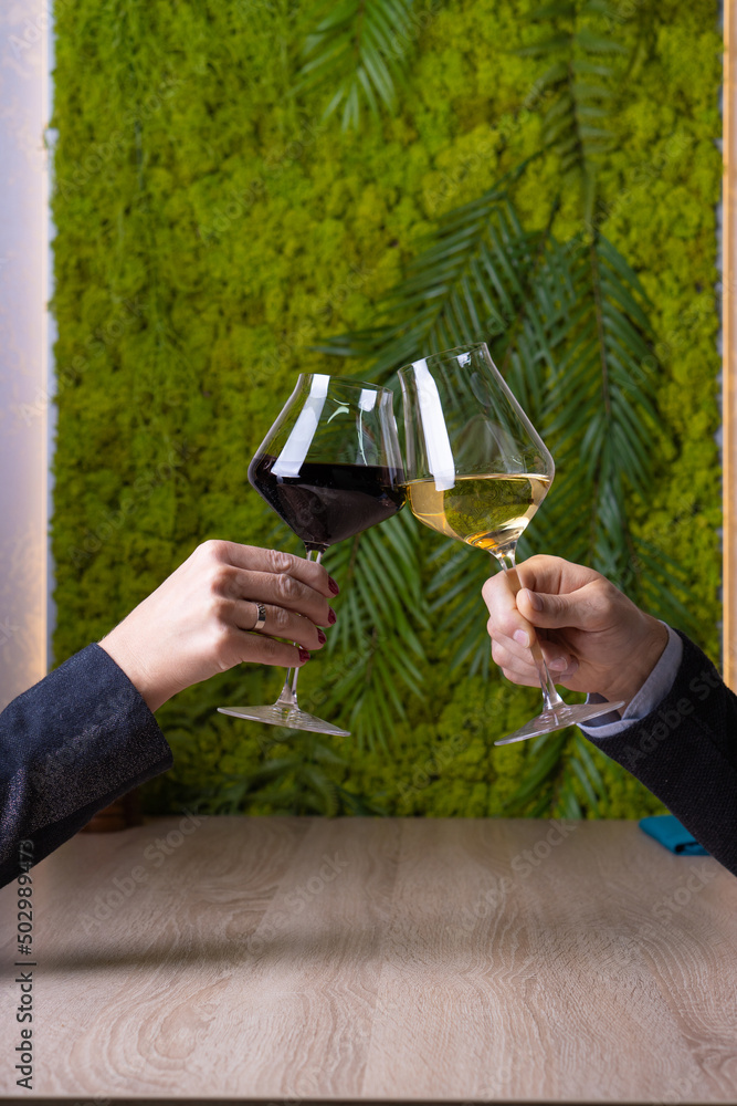 A man and a woman clink glasses of wine. Red and white wine. A man and a woman clink glasses of wine. Red and white wine.