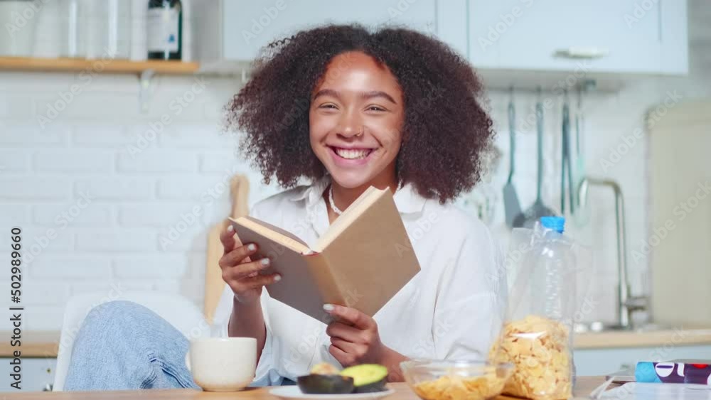 Young happy African American woman laughs reading book by favorite ...