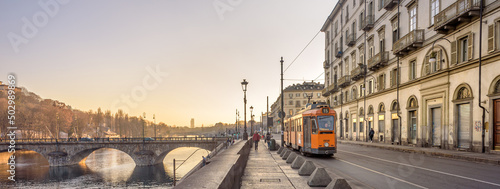 Turin, Italy. February, 15, 2022. View at sunset on the Po river In the distance the ancient Vittorio Emanuele I bridge and a tram passing in Lungo Po Luigi Cadorna street. Banner header.