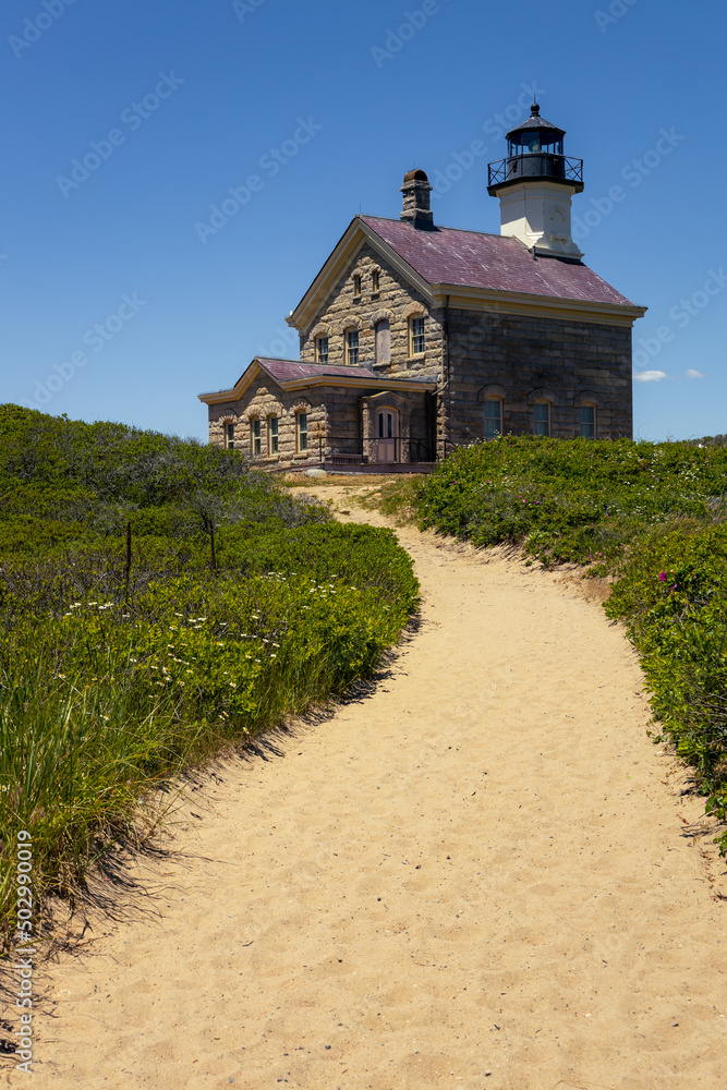 Lighthouse withe lush green and a sand pathway vertical Lighthouse withe lush green and a sand pathway vertical