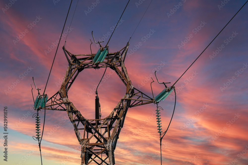 High voltage power line pylon, high voltage electrical transmission tower on colorful sunset sky, copy space