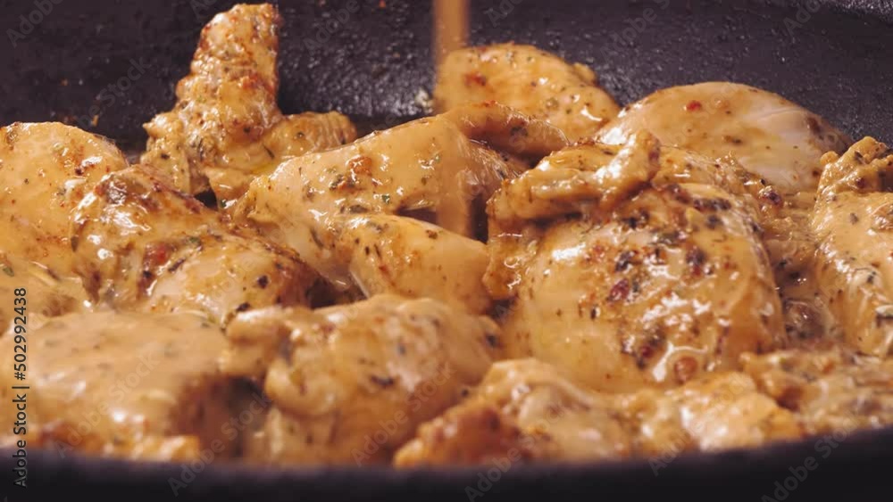 Soy sauce is poured into pieces of chicken in spices fried in a frying pan. Close-up Soy sauce is poured into pieces of chicken in spices fried in a frying pan. Close-up