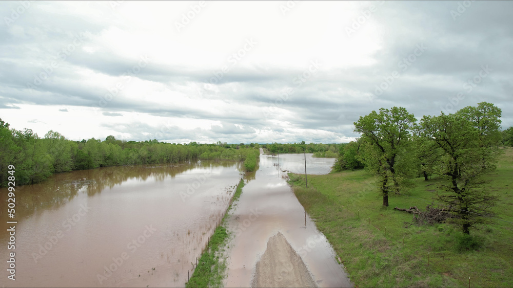 Aerial view of a rural road and pastureland under water after heavy rains inundated the region over several days; leaving many roads impassable for traffic due to flooding.