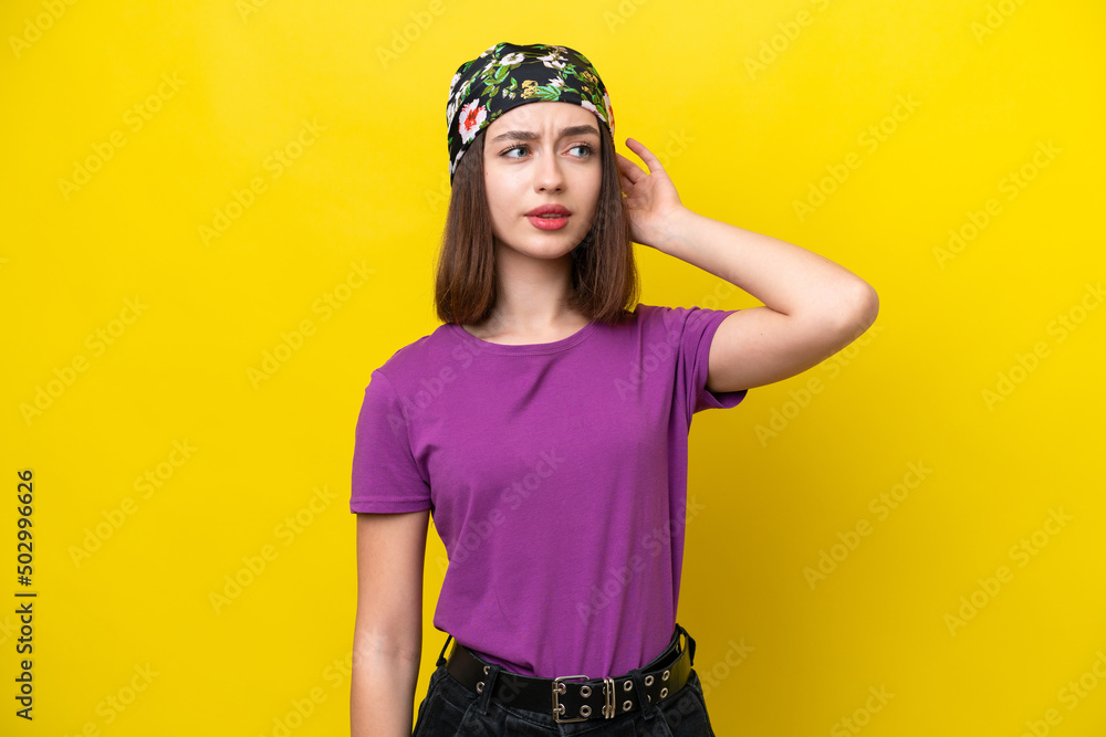 Fototapeta premium Young Ukrainian woman isolated on yellow background having doubts