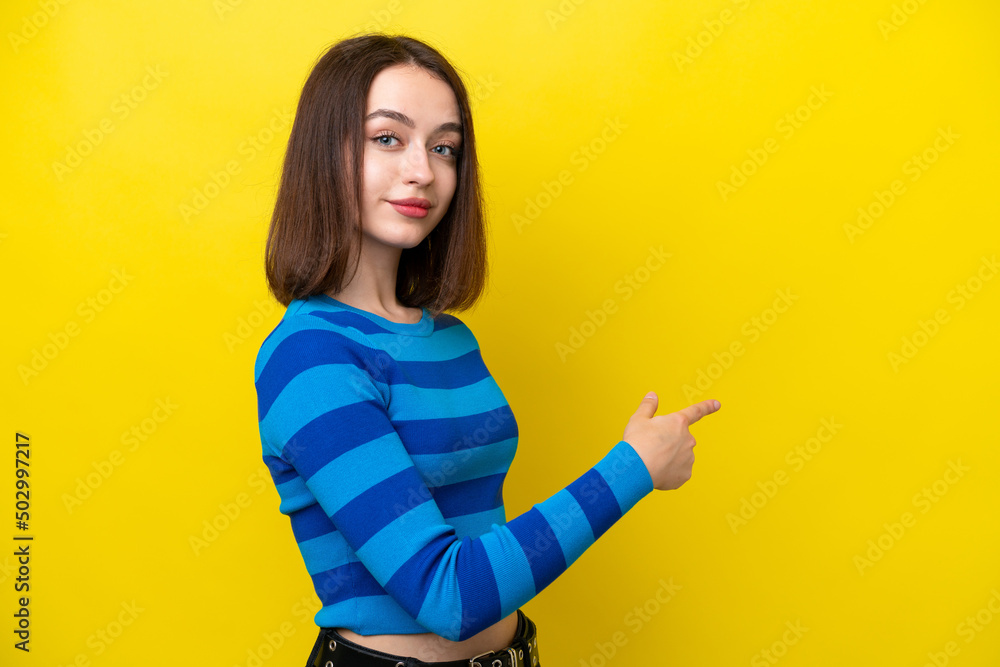 Fototapeta premium Young Ukrainian woman isolated on yellow background pointing back
