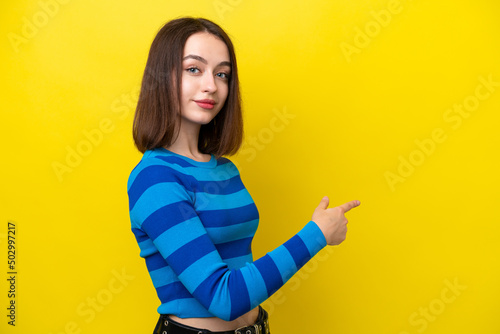 Foto Young Ukrainian woman isolated on yellow background pointing back
