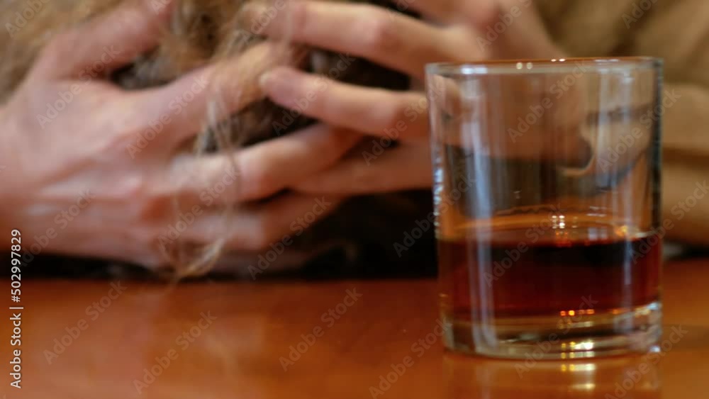 shaking woman hand reaching of glass with whiskey standing on a wooden table, woman's alcoholism problem shaking woman hand reaching of glass with whiskey standing on a wooden table, woman's alcoholism problem