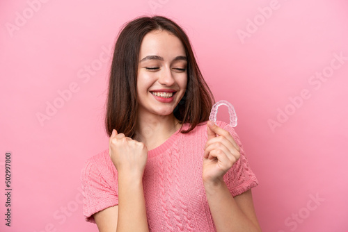 Fotografia Young Ukrainian woman holding invisible braces isolated on pink background celeb