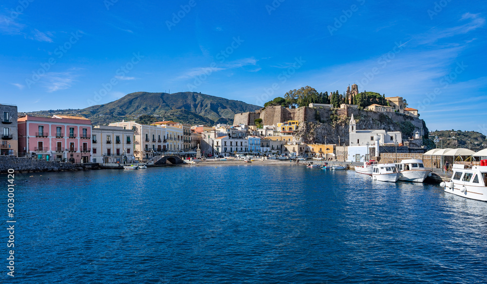 Sizilien: Lipari Stadt - der alte kleine Hafen vom Boot, Wasser aus betrachtet mit Kirche, Burgberg, Kastell, historischen Gebäuden und Booten
