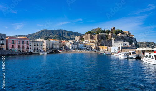 Sizilien: Lipari Stadt - der alte kleine Hafen vom Boot, Wasser aus betrachtet mit Kirche, Burgberg, Kastell, historischen Gebäuden und Booten photo