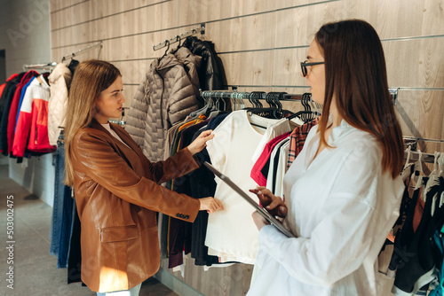 Professional Shopping Assistant Using Digital Tablet Helping Female Client Buy Clothes And Improve Personal Style In Store. Free Space