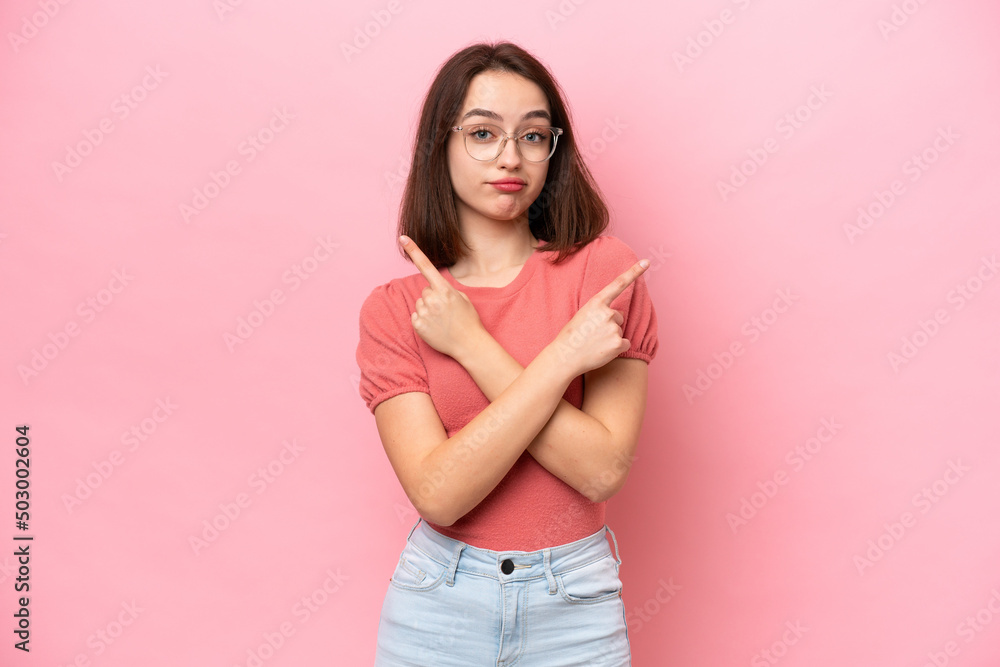 Young Ukrainian woman isolated on pink background pointing to the laterals having doubts Young Ukrainian woman isolated on pink background pointing to the laterals having doubts