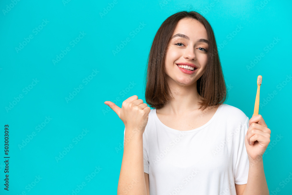 Young Ukrainian woman brushing teeth isolated on blue background pointing to the side to present a product Young Ukrainian woman brushing teeth isolated on blue background pointing to the side to present a product
