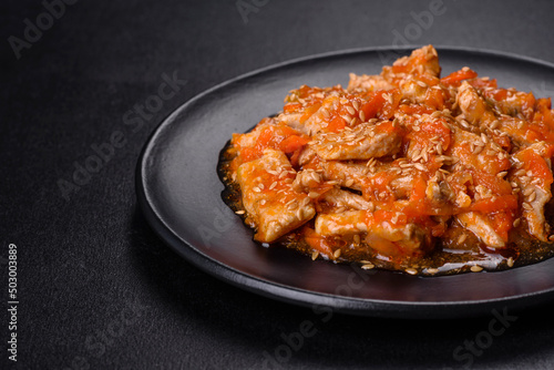 Teriyaki chicken with sauce, sesame, herbs and spices on a dark background
