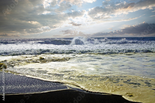 Beautiful rough ocean landscape, black lava sand beach, foamy white surf, breaking waves with sea spray, evening sky horizon clouds - Cobquecura, Chile, Pacific Coast photo