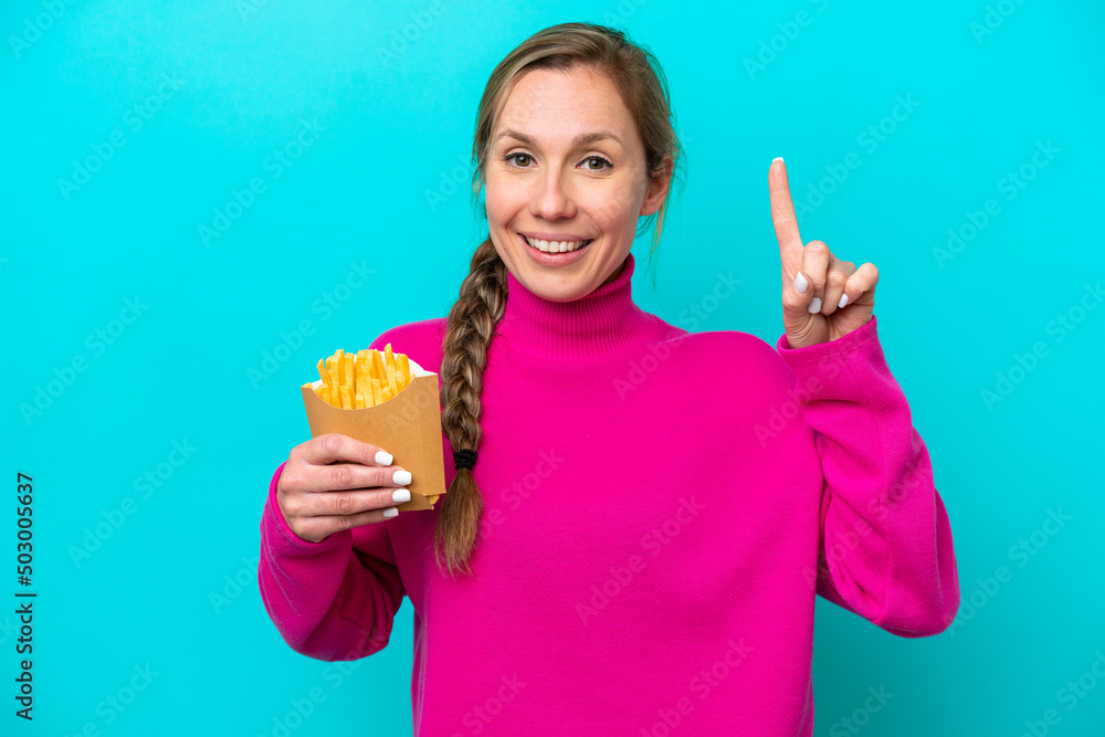 Young caucasian woman holding fried chips isolated on blue background showing and lifting a finger in sign of the best Young caucasian woman holding fried chips isolated on blue background showing and lifting a finger in sign of the best